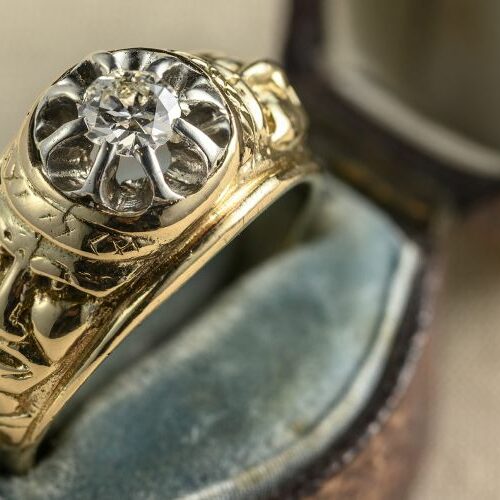 Anello in oro con diamante taglio antico di ct. 0,40 e due volti maschili cesellati ai lati lungo il gambo. Epoca fine '800