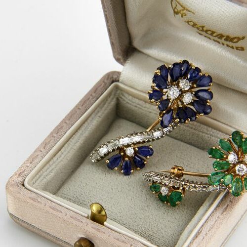Coppia di spille in oro, smeraldi, zaffiri e diamanti a tralcio di fiore. Epoca anni '50