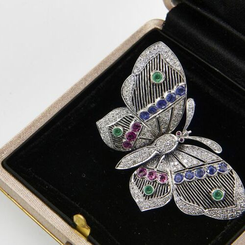 Spilla a clips a farfalla in oro bianco, smeraldi, rubini, zaffiri e diamanti. Epoca anni '30