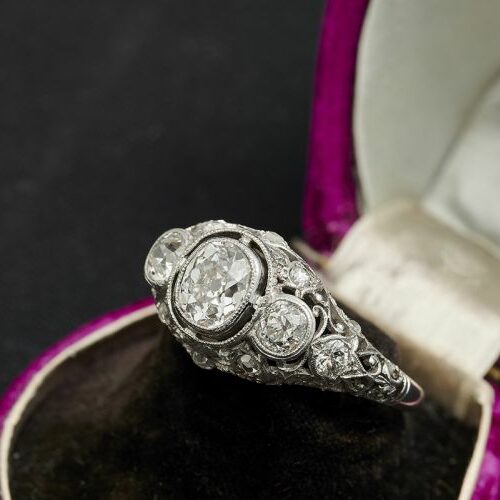 Anello in oro bianco traforato con un diamante taglio cuscino di ct. 1,10 ca e due diamanti laterali di taglio vecchio di ct. 0,40 caduno e diamantini. Epoca anni '20
