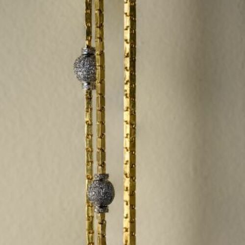 Lunga collana in oro giallo 22 kt recante due boulles in oro bianco a pavè di diamanti di ct. 4 complessivi. Epoca anni' 60